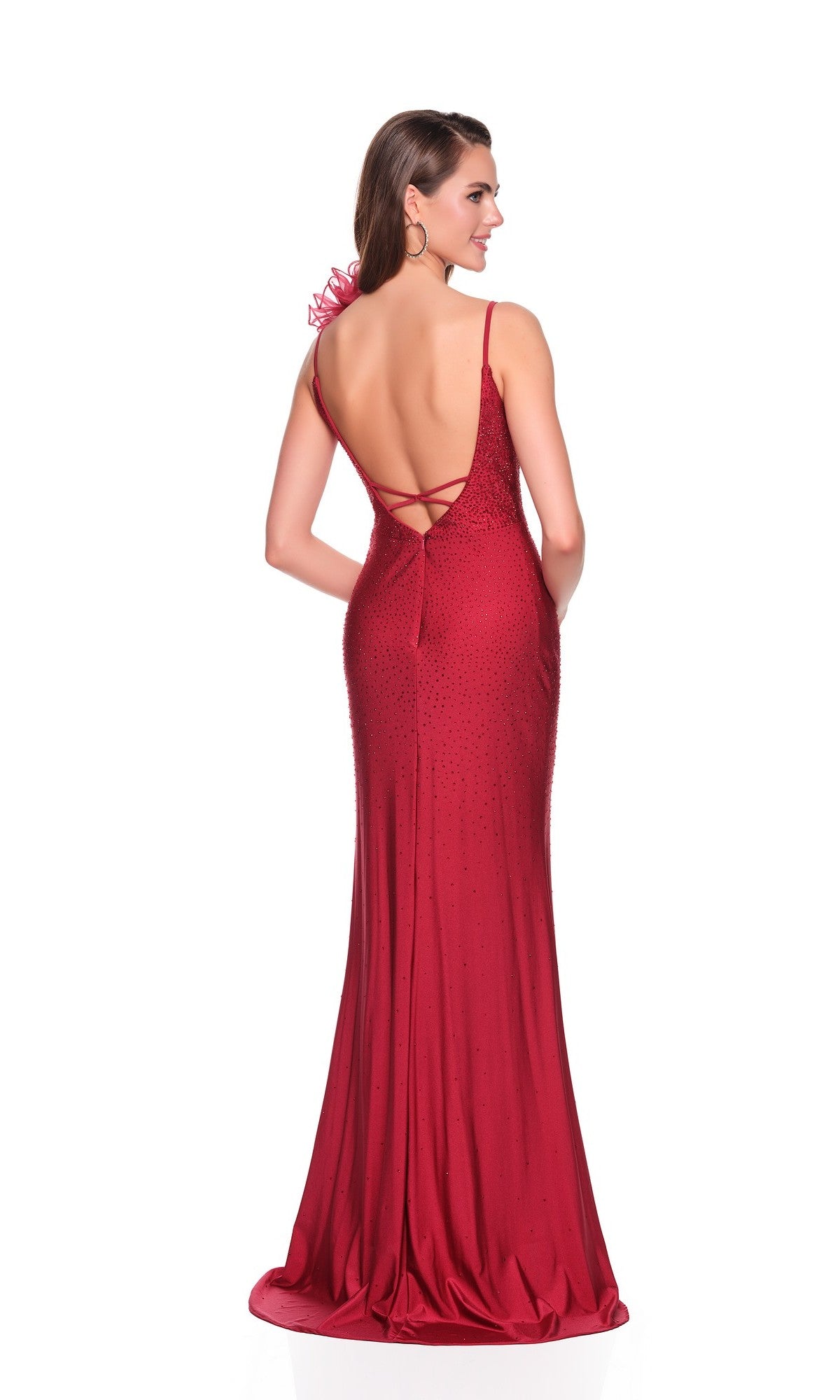 A woman poses with hands in pockets, wearing the Dave and Johnny 12412 Long Prom Dress—a floor-length, backless burgundy gown with thin straps, crisscross detailing, and subtle embellishments against a white background.